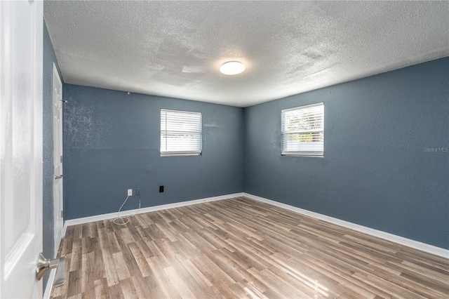 unfurnished room with hardwood / wood-style flooring, plenty of natural light, and a textured ceiling