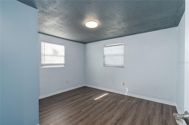 empty room featuring a textured ceiling and dark wood-type flooring