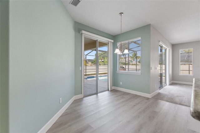 unfurnished dining area featuring light hardwood / wood-style flooring and a chandelier