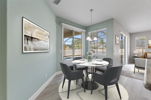 dining space with light hardwood / wood-style flooring, plenty of natural light, and a notable chandelier