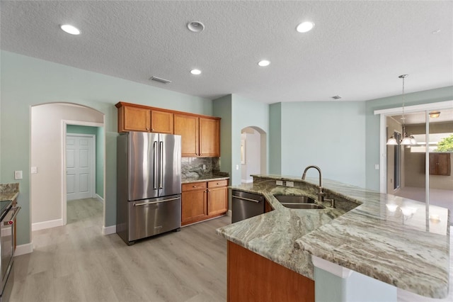 kitchen featuring light stone countertops, backsplash, a textured ceiling, stainless steel appliances, and sink