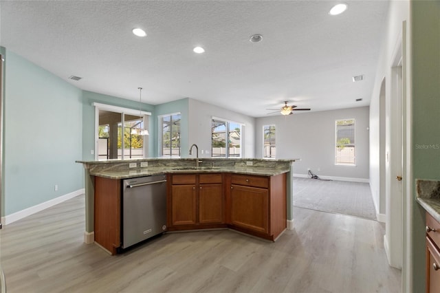 kitchen with dishwasher, sink, an island with sink, decorative light fixtures, and light wood-type flooring