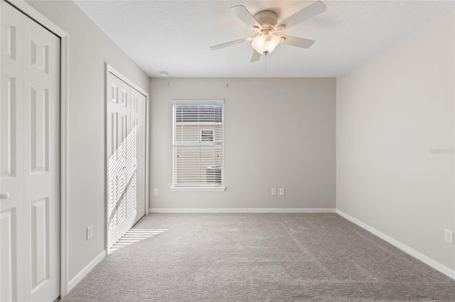 unfurnished bedroom with ceiling fan, light carpet, and two closets