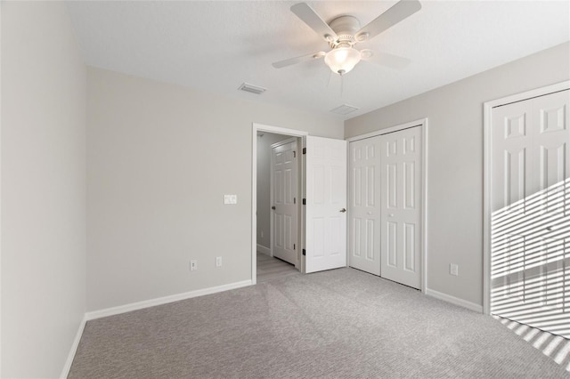 unfurnished bedroom featuring two closets, light colored carpet, and ceiling fan