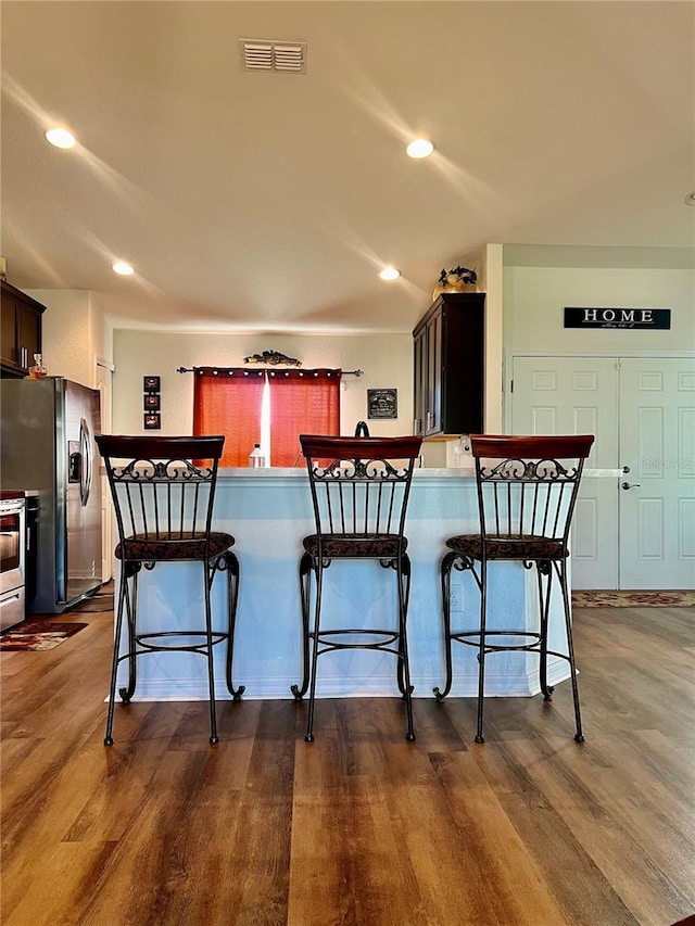 kitchen featuring kitchen peninsula, stainless steel fridge with ice dispenser, and a breakfast bar