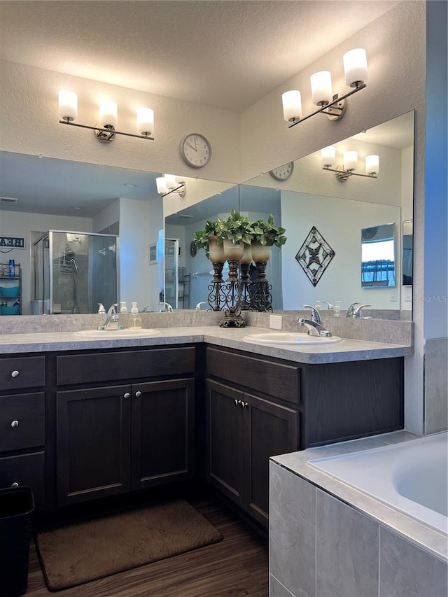 bathroom with plus walk in shower, a textured ceiling, vanity, and hardwood / wood-style flooring