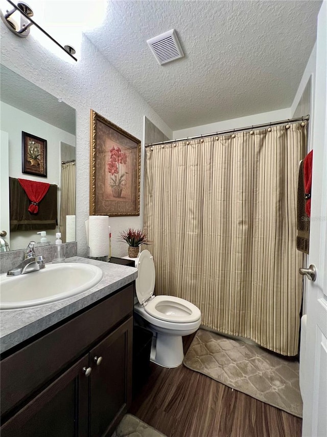 bathroom with toilet, vanity, a textured ceiling, and hardwood / wood-style flooring