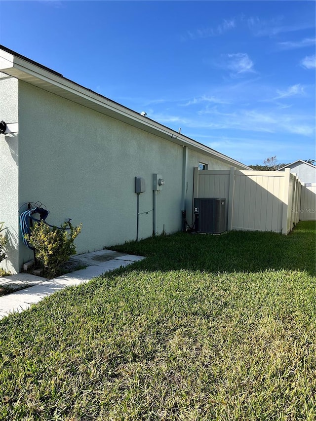 view of side of home with a lawn and central air condition unit