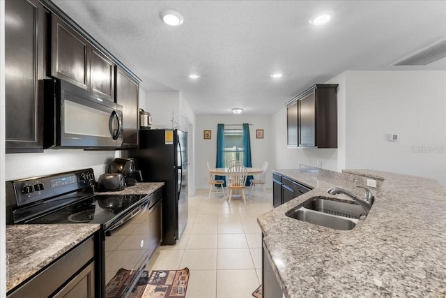 kitchen with a textured ceiling, dark brown cabinetry, sink, black appliances, and light tile patterned floors