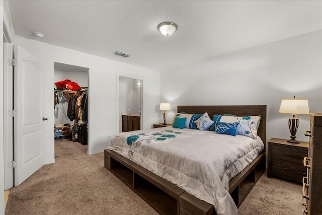 carpeted bedroom with a walk in closet, ensuite bath, and a closet