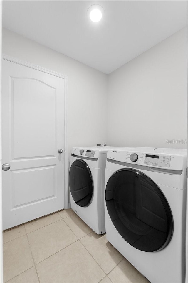 laundry area with independent washer and dryer and light tile patterned floors