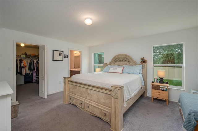 carpeted bedroom with a walk in closet, ensuite bathroom, and a closet