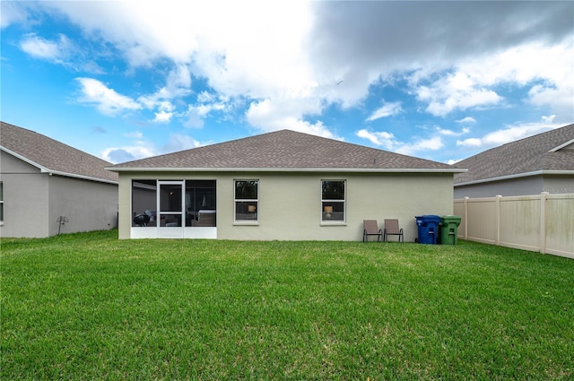 rear view of property with a lawn and a sunroom