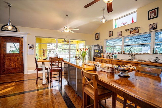 dining space featuring ceiling fan, sink, hardwood / wood-style floors, and vaulted ceiling