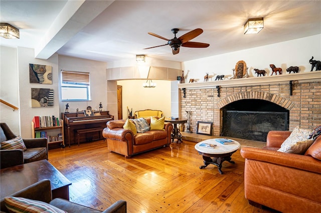 living room with ceiling fan, wood-type flooring, and a brick fireplace