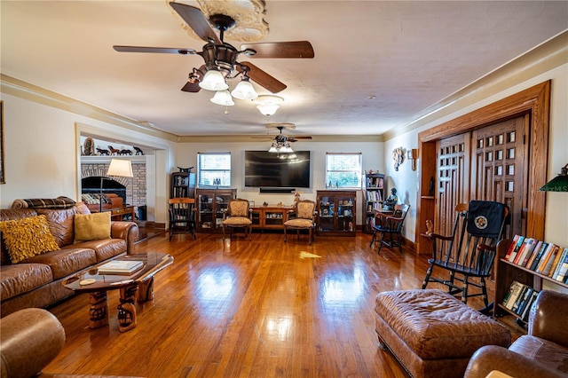 living room featuring ceiling fan, wood-type flooring, and a fireplace