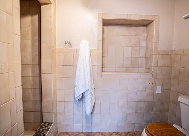 bathroom with tiled shower, tile walls, and toilet