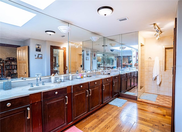 bathroom with a skylight, hardwood / wood-style floors, vanity, and walk in shower