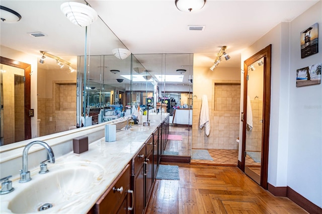 bathroom with parquet floors, vanity, and walk in shower