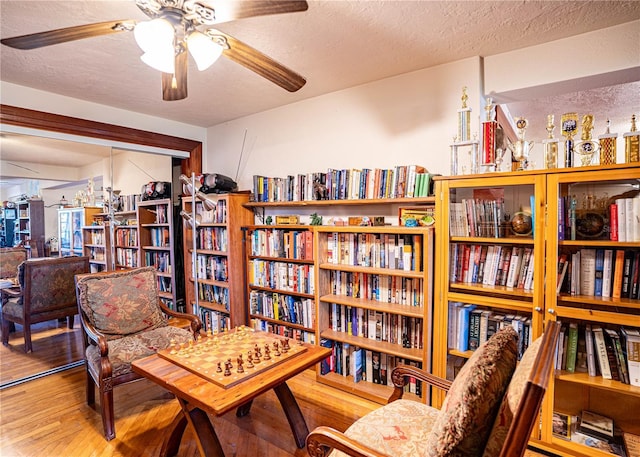 living area featuring ceiling fan, wood-type flooring, and a textured ceiling