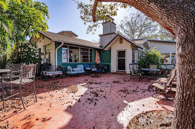 back of property with an outdoor living space and a patio