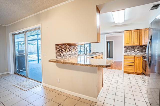 kitchen with sink, a textured ceiling, tasteful backsplash, light tile patterned flooring, and kitchen peninsula