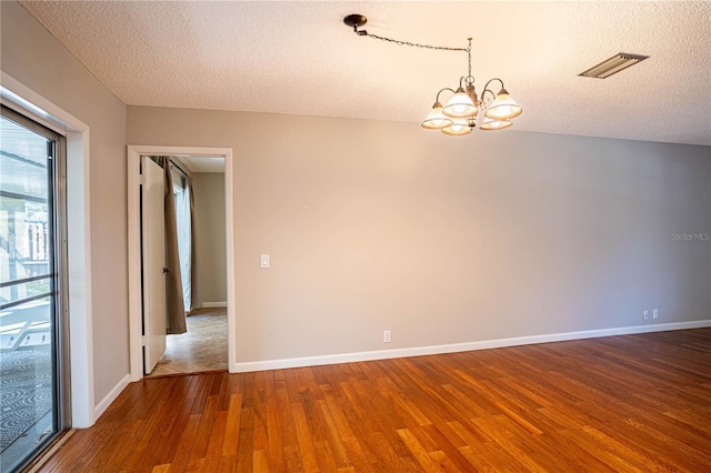 spare room featuring hardwood / wood-style flooring, a textured ceiling, and an inviting chandelier