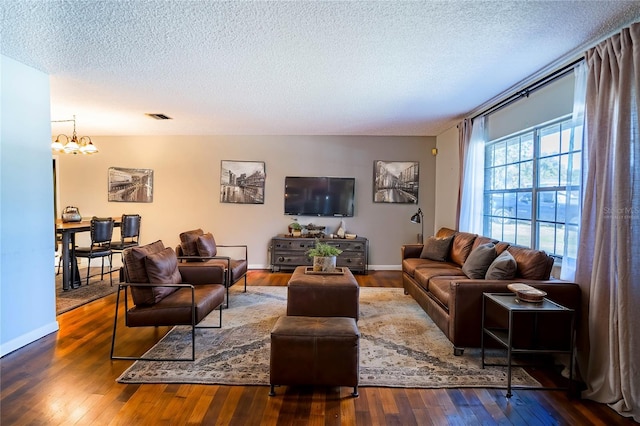 living room with a chandelier, a textured ceiling, and dark hardwood / wood-style floors