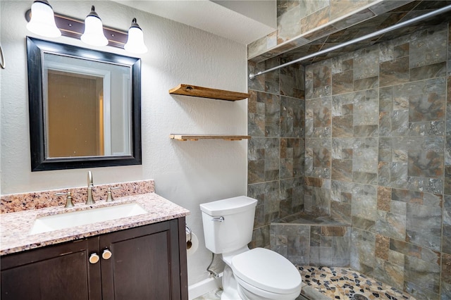 bathroom featuring tiled shower, vanity, and toilet