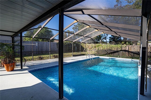 view of swimming pool with glass enclosure and a patio