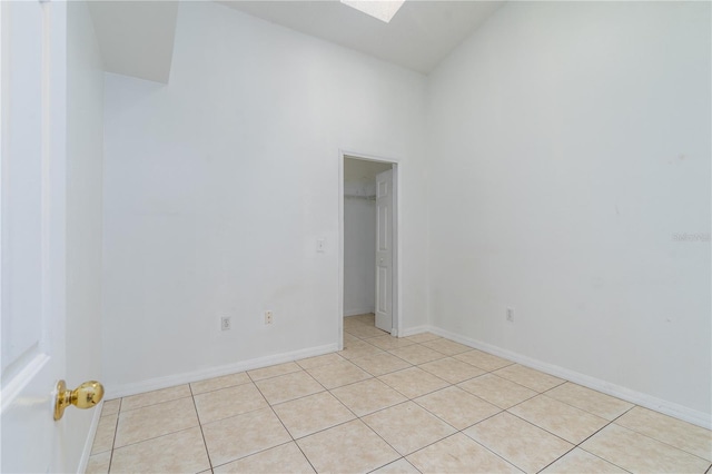 unfurnished room featuring lofted ceiling with skylight and light tile patterned floors