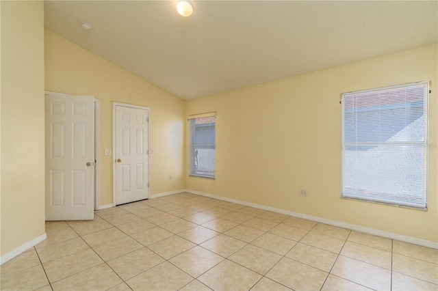 empty room with light tile patterned flooring and lofted ceiling