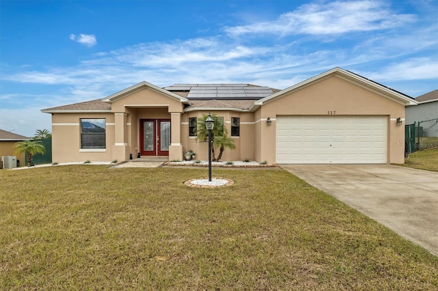 view of front of property with a front yard, solar panels, and a garage