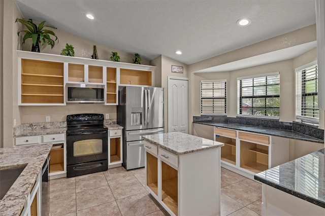 kitchen with light stone counters, stainless steel appliances, vaulted ceiling, a kitchen island, and light tile patterned flooring