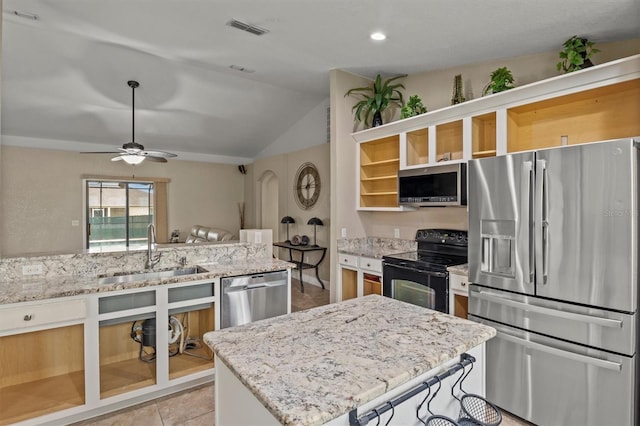 kitchen featuring ceiling fan, sink, light stone counters, lofted ceiling, and appliances with stainless steel finishes