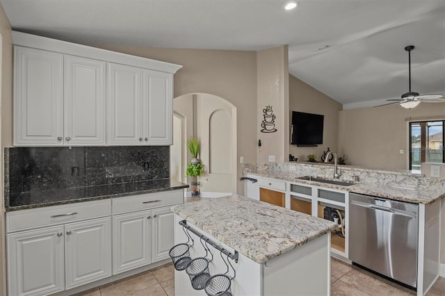 kitchen featuring kitchen peninsula, white cabinetry, dishwasher, and vaulted ceiling