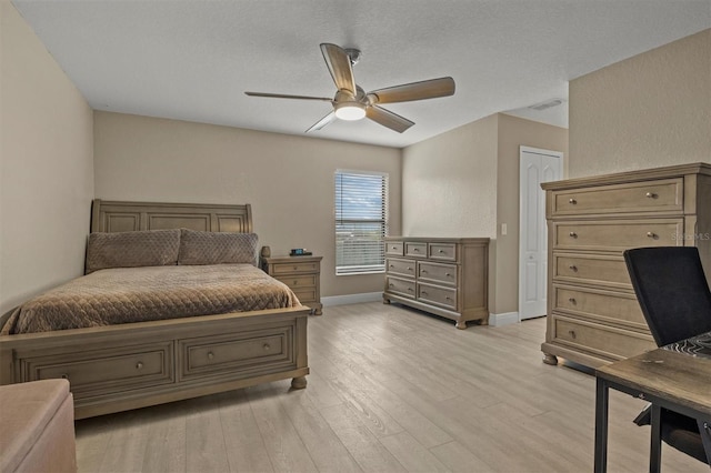 bedroom featuring ceiling fan, a closet, a textured ceiling, and light wood-type flooring