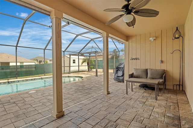 view of patio with a fenced in pool, glass enclosure, and ceiling fan