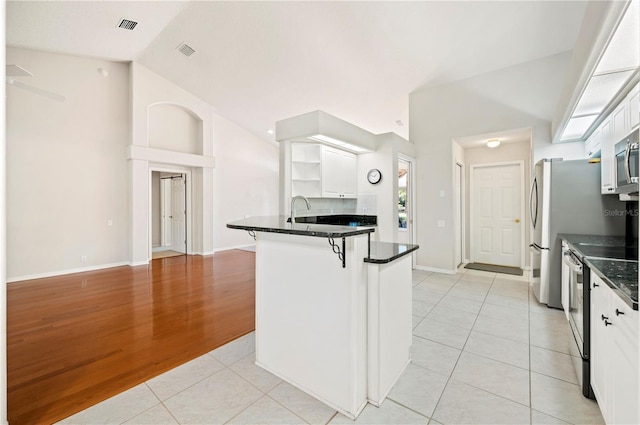 kitchen featuring white cabinetry, light tile patterned floors, vaulted ceiling, a breakfast bar, and stainless steel range with electric cooktop