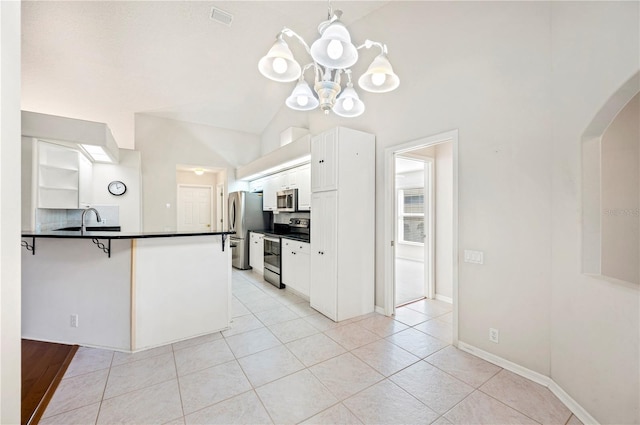 kitchen featuring white cabinets, vaulted ceiling, decorative backsplash, appliances with stainless steel finishes, and kitchen peninsula