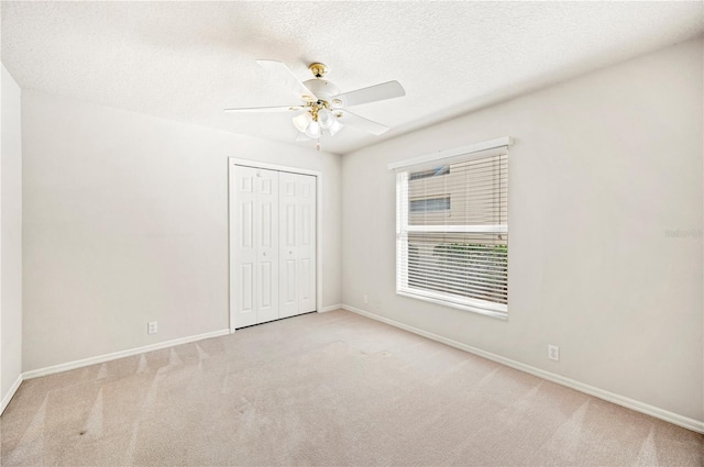 unfurnished bedroom with light carpet, a textured ceiling, a closet, and ceiling fan