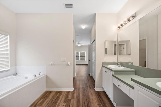 bathroom with vanity, ceiling fan, wood-type flooring, and tiled bath