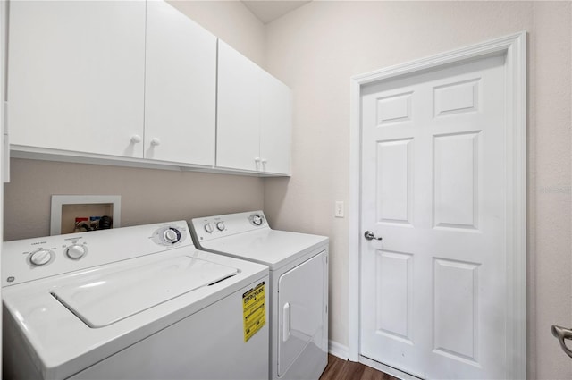 clothes washing area featuring cabinets, washing machine and dryer, and dark wood-type flooring