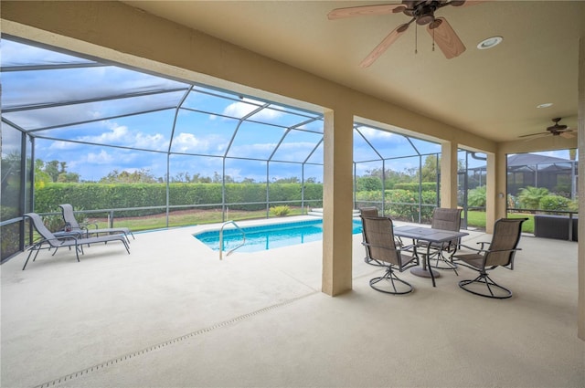 view of pool featuring glass enclosure, ceiling fan, and a patio