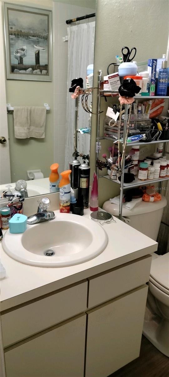 bathroom featuring hardwood / wood-style floors, vanity, toilet, and curtained shower