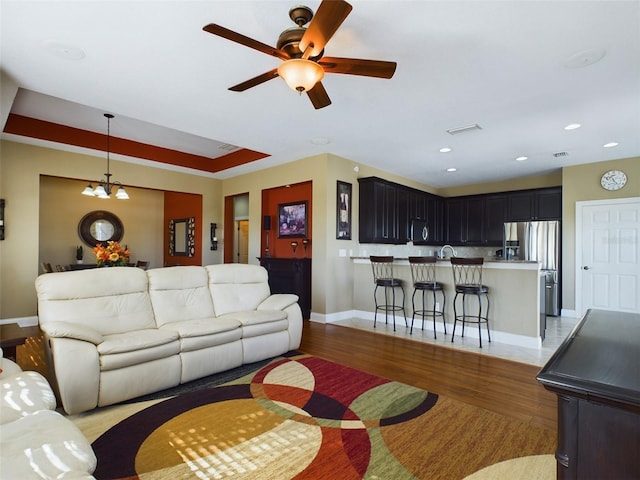 living room featuring ceiling fan with notable chandelier and light hardwood / wood-style flooring