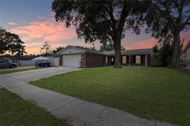 ranch-style home featuring a garage and a yard