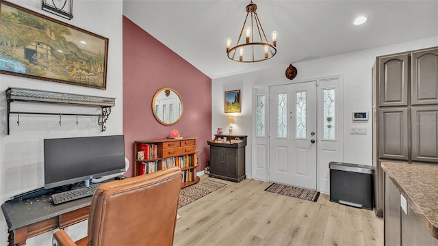 entrance foyer featuring an inviting chandelier, light hardwood / wood-style floors, and lofted ceiling