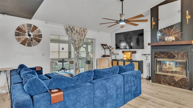 living room with a premium fireplace, vaulted ceiling, ceiling fan, and light hardwood / wood-style flooring