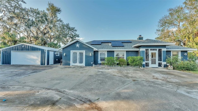 view of front of property featuring french doors, a garage, an outdoor structure, and solar panels